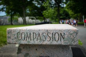 Grey concrete bench with the word compassion engraved on it.