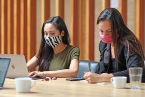 Two women wearing masks working at a table