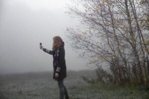 A woman holds up a compass on a foggy landscape