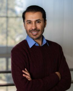Photo of Moshin Jat, a man wearing a black sweater over a blue collared shirt
