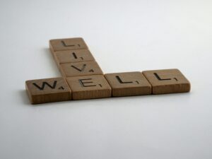 Scrabble tiles spell the words LIVE WELL